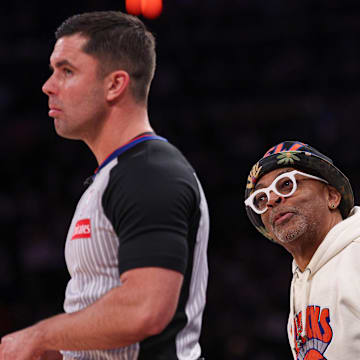Apr 6, 2025; New York, New York, USA; American actor and director Spike Lee tends behind referee Andy Nagy (83) during the second half of the game against the Phoenix Suns at Madison Square Garden. Mandatory Credit: Vincent Carchietta-Imagn Images