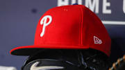 May 26, 2023; Atlanta, Georgia, USA; A detailed view of a Philadelphia Phillies hat and glove on the bench against the Atlanta Braves in the seventh inning at Truist Park. 