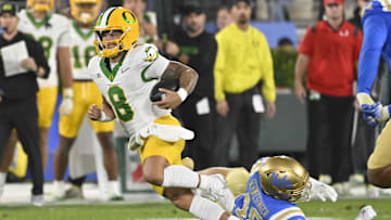 Sep 28, 2024; Pasadena, California, USA; Oregon Ducks quarterback Dillon Gabriel (8) runs past UCLA Bruins linebacker Carson Schwesinger (49) during the second quarter at Rose Bowl. Mandatory Credit: Robert Hanashiro-Imagn Images