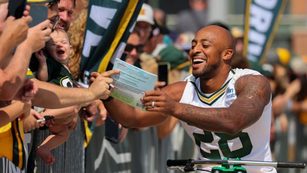 Green Bay Packers running back A.J. Dillon signs a copy of his children’s book before practice.