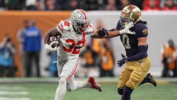 Jan 20, 2025; Atlanta, GA, USA; Ohio State Buckeyes running back TreVeyon Henderson (32) stiff arms Notre Dame Fighting Irish safety Xavier Watts (0) in the first half in the CFP National Championship college football game at Mercedes-Benz Stadium. Mandatory Credit: Dale Zanine-Imagn Images
