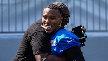 Detroit Lions wide receiver Amon-Ra St. Brown (14) hugs Lions great Lomas Brown after practice during training camp at Meijer Performance Center in Allen Park on Monday, July 21, 2025.
