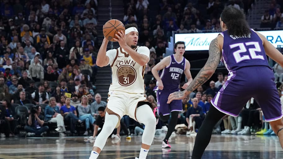 Golden State Warriors guard Seth Curry looks to pass against Sacramento Kings guard Devin Carter.
