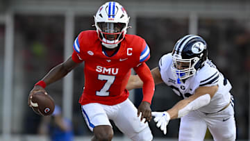 Sep 6, 2024; Dallas, Texas, USA; Southern Methodist Mustangs quarterback Kevin Jennings (7) eludes the tackle of Brigham Young Cougars linebacker Choe Bryant-Strother (33) during the first half at Gerald J. Ford Stadium. Mandatory Credit: Jerome Miron-Imagn Images