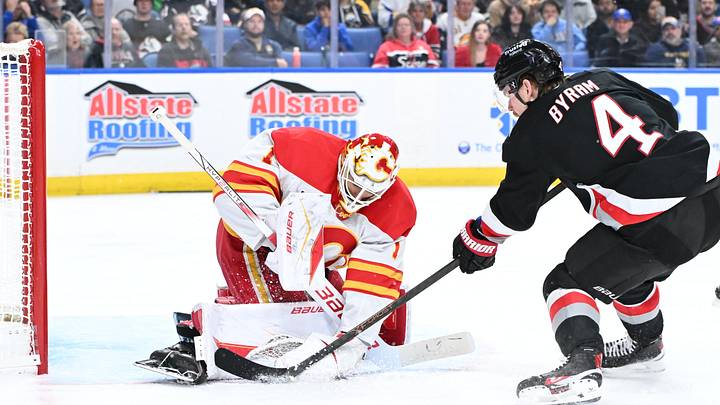 Nov 19, 2025; Buffalo, New York, USA; Calgary Flames goaltender Devin Cooley (1) blocks a shot by Buffalo Sabres defenseman Bowen Byram (4) in the second period at KeyBank Center. Mandatory Credit: Mark Konezny-Imagn Images