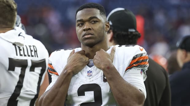 Football player grabs his jersey and shoulder pads around his collar.