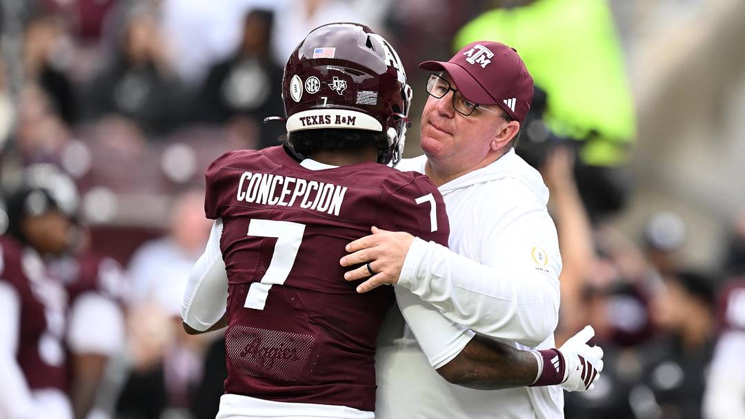 Dec 20, 2025; College Station, TX, USA; Texas A&M Aggies head coach Mike Elko hugs Texas A&M Aggies wide receiver KC Concepcion (7) prior to the game against the Miami Hurricanes during the first round of the CFP National Playoff at Kyle Field. Mandatory Credit: Maria Lysaker-Imagn Images