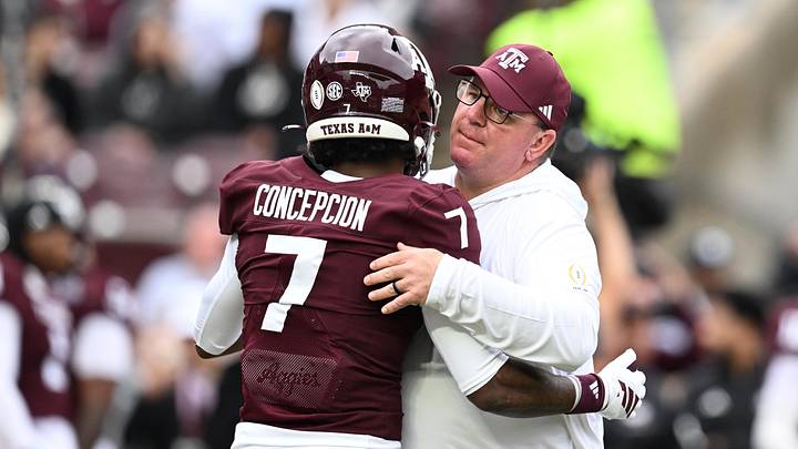 Dec 20, 2025; College Station, TX, USA; Texas A&M Aggies head coach Mike Elko hugs Texas A&M Aggies wide receiver KC Concepcion (7) prior to the game against the Miami Hurricanes during the first round of the CFP National Playoff at Kyle Field. Mandatory Credit: Maria Lysaker-Imagn Images
