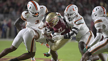 Oct 4, 2025; Tallahassee, Florida, USA; Miami Hurricanes defensive lineman Rueben Bain Jr. (4) tackles Florida State Seminoles running back Gavin Sawchuk (27) during the first half at Doak S. Campbell Stadium. Mandatory Credit: Melina Myers-Imagn Images
