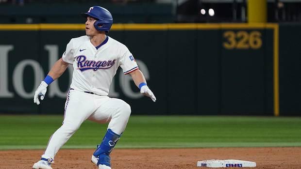 Texas Rangers Outfielder Sam Haggerty Rounds Second Base depois de atingir um duplo em um uniforme branco e capacete azul