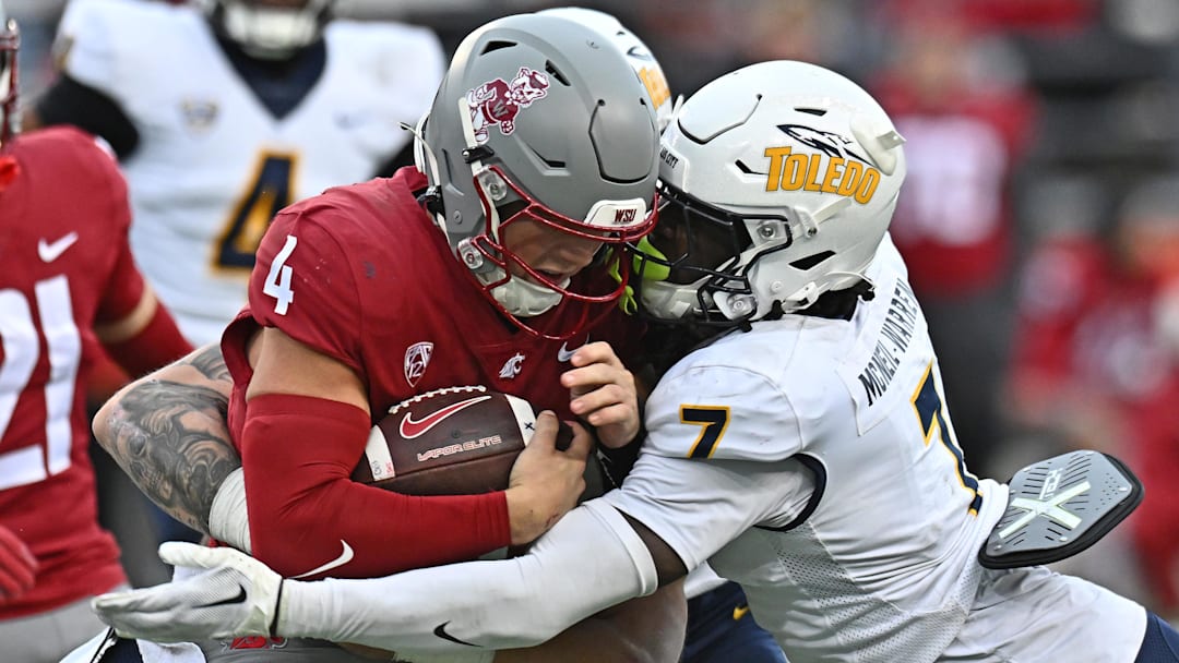 Oct 25, 2025; Pullman, Washington, USA; Washington State Cougars quarterback Zevi Eckhaus (4) is tackled by Toledo Rockets safety Emmanuel McNeil-Warren (7) in the second half at Gesa Field at Martin Stadium. Mandatory Credit: James Snook-Imagn Images
