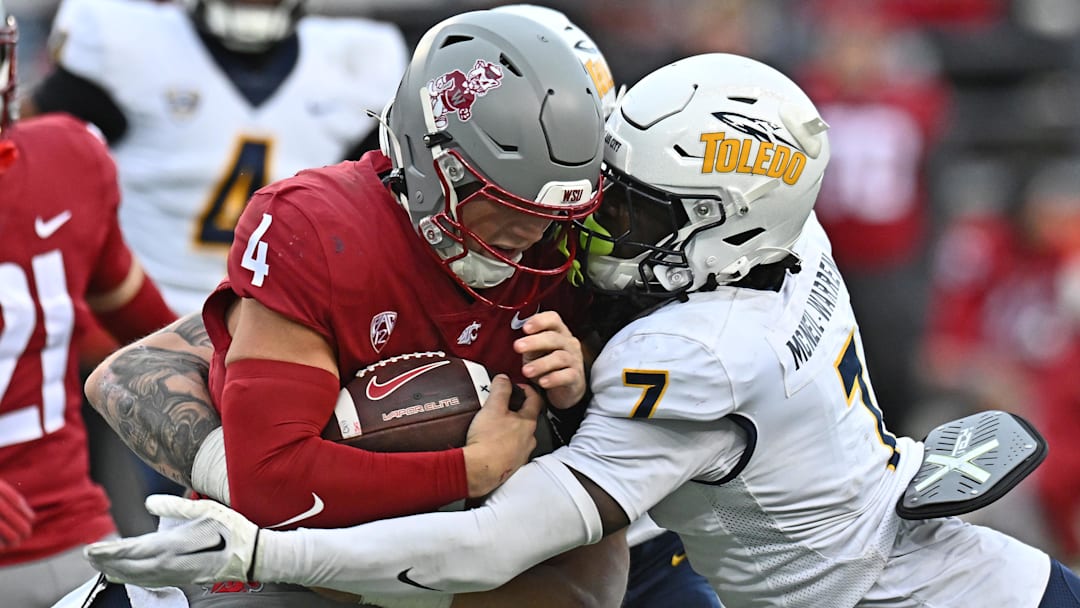 Oct 25, 2025; Pullman, Washington, USA; Washington State Cougars quarterback Zevi Eckhaus (4) is tackled by Toledo Rockets safety Emmanuel McNeil-Warren (7) in the second half at Gesa Field at Martin Stadium. Mandatory Credit: James Snook-Imagn Images
