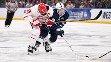 Boston University men's hockey forward Shane Lachance (18) and Penn State men's hockey forward Aiden Fink (18) collide while battling for the puck during the second of the Frozen Four semifinals