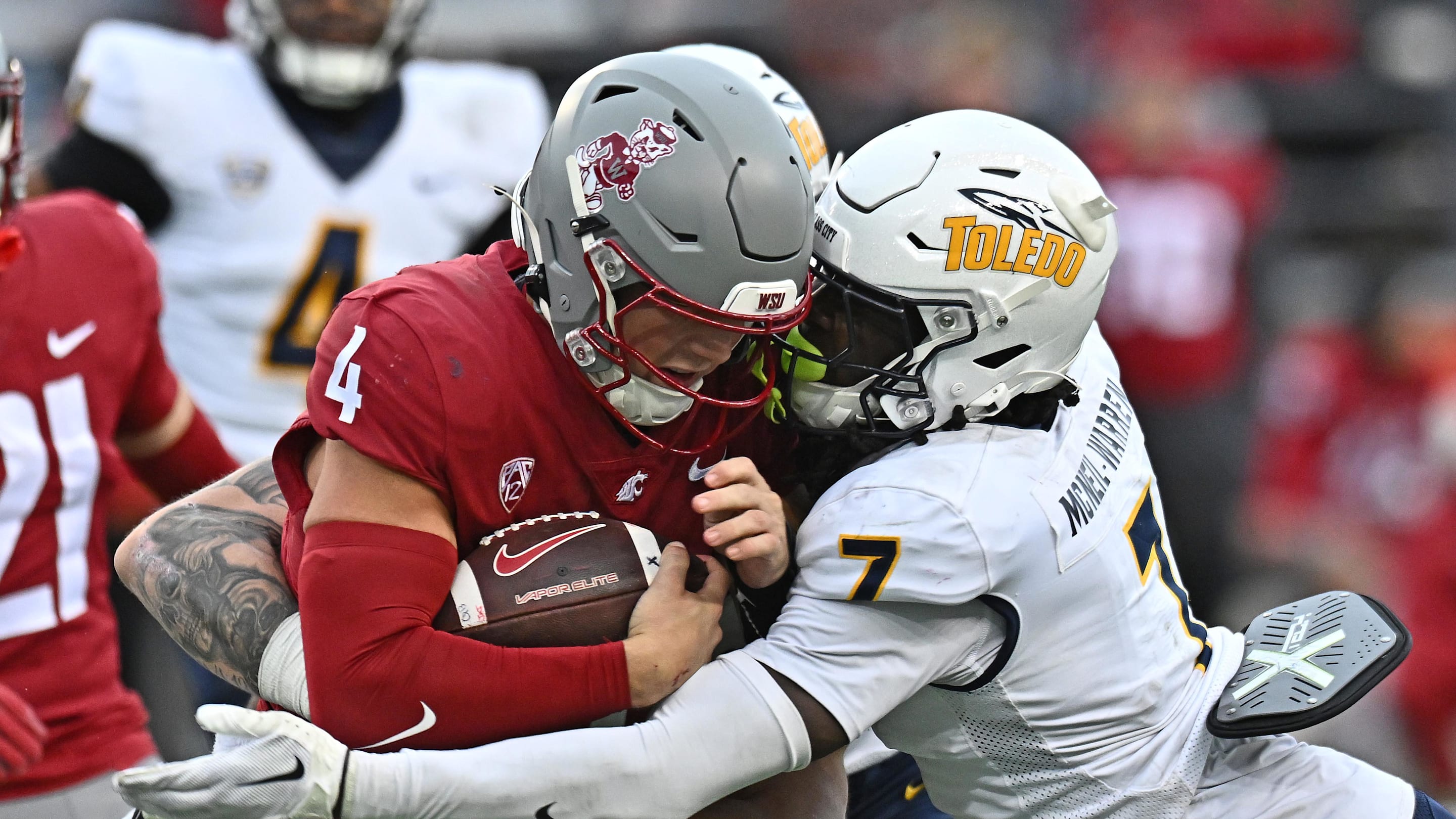 Oct 25, 2025; Pullman, Washington, USA; Washington State Cougars quarterback Zevi Eckhaus (4) is tackled by Toledo Rockets safety Emmanuel McNeil-Warren (7) in the second half at Gesa Field at Martin Stadium. Mandatory Credit: James Snook-Imagn Images