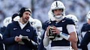 Penn State Nittany Lions quarterback Drew Allar (15) warms up on the sideline while listening to quarterback coach Danny O'Brien (left) during the first quarter against the SMU Mustangs in the first round of the College Football Playoff at Beaver Stadium. 