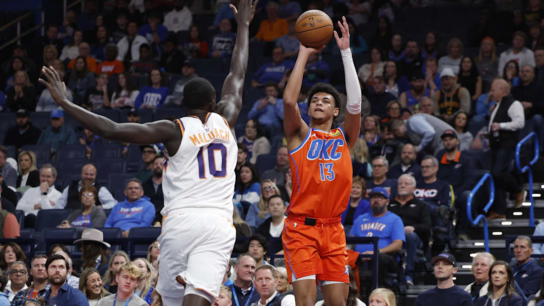 Dec 10, 2025; Oklahoma City, Oklahoma, USA; Oklahoma City Thunder forward Ousmane Dieng (13) shoots a three point basket as Phoenix Suns center Khaman Maluach (10) defends during the second half at Paycom Center. Mandatory Credit: Alonzo Adams-Imagn Images