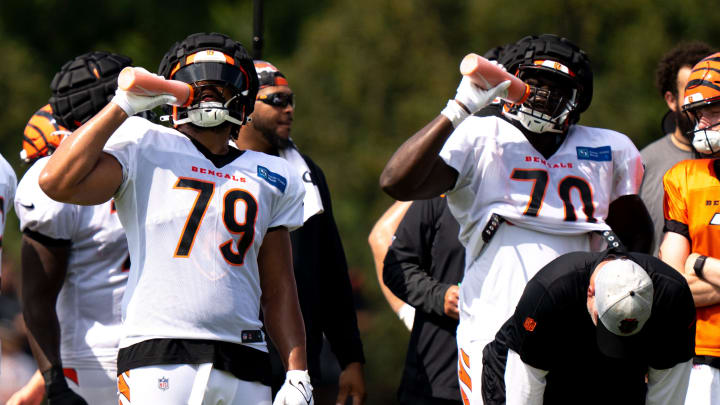 Cincinnati Bengals defensive end Jackson Carman (79) and Cincinnati Bengals offensive tackle D'Ante Smith (70) drink water while practicing in 91 degree weather at the Cincinnati Bengals NFL training camp practice in Cincinnati on Thursday, Aug. 3, 2023.