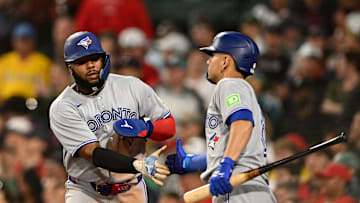 Jun 27, 2025; Boston, Massachusetts, USA; Toronto Blue Jays first baseman Vladimir Guerrero Jr. (27) high-fives second baseman Andres Gimenez (0) after scoring a run against the Boston Red Sox during the eighth inning at Fenway Park. Mandatory Credit: Brian Fluharty-Imagn Images