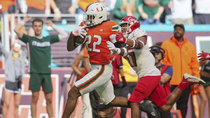 Nov 18, 2023; Miami Gardens, Florida, USA; Miami Hurricanes running back Mark Fletcher Jr. (22) runs with the football against Louisville Cardinals defensive back Devin Neal (27) during the third quarter at Hard Rock Stadium. Mandatory Credit: Sam Navarro-Imagn Images