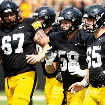 Aug 9, 2025; Iowa offensive linemen Gennings Dunker (67) Kade Pieper (58) and Logan Jones (65) run a drill during the Hawkeyes Kids Day NCAA football open practice at Kinnick Stadium in Iowa City, Iowa. Mandatory Credit: Joseph Cress for the Des Moines Register