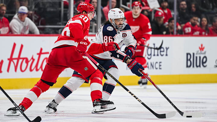 Feb 27, 2025; Detroit, Michigan, USA; Columbus Blue Jackets right wing Kirill Marchenko (86) brings the puck up ice against Detroit Red Wings defenseman Albert Johansson (20) during the game at Little Caesars Arena. Mandatory Credit: Tim Fuller-Imagn Images