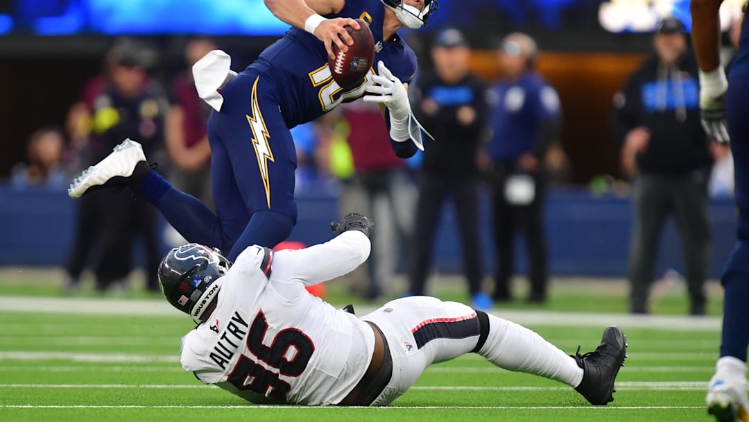 Dec 27, 2025; Inglewood, California, USA;  Los Angeles Chargers quarterback Justin Herbert (10) is sacked by Houston Texans defensive end Denico Autry (96) during the first half at SoFi Stadium. Mandatory Credit: Gary A. Vasquez-Imagn Images