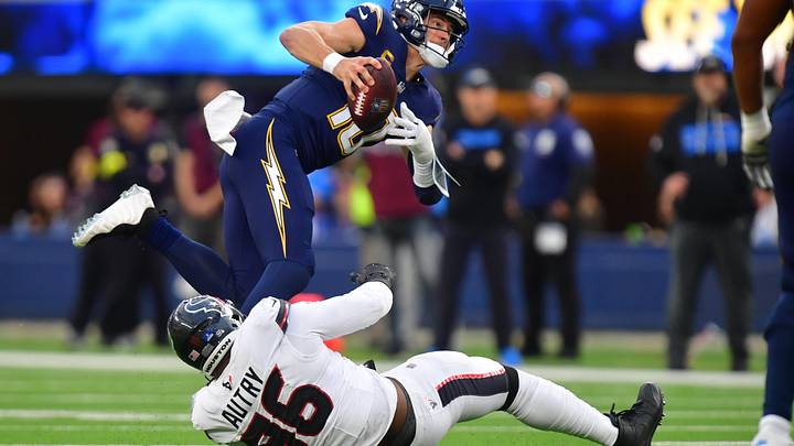 Dec 27, 2025; Inglewood, California, USA;  Los Angeles Chargers quarterback Justin Herbert (10) is sacked by Houston Texans defensive end Denico Autry (96) during the first half at SoFi Stadium. Mandatory Credit: Gary A. Vasquez-Imagn Images
