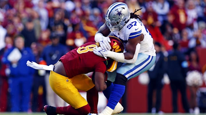 Washington Commanders running back Brian Robinson Jr. is tackled by Dallas Cowboys defensive tackle Osa Odighizuwa.