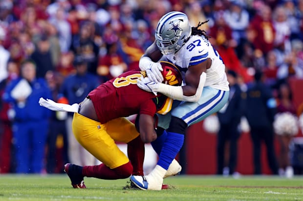 Washington Commanders running back Brian Robinson Jr. is tackled by Dallas Cowboys defensive tackle Osa Odighizuwa.