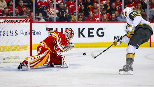Hockey goalie in red uniform makes save on shot attemp
