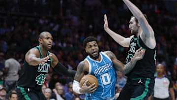 Nov 2, 2024; Charlotte, North Carolina, USA; Charlotte Hornets forward Miles Bridges (0)  drives between Boston Celtics center Luke Kornet (40) and center Al Horford (42) during the second half at Spectrum Center. Mandatory Credit: Nell Redmond-Imagn Images