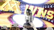 Dec 29, 2022; Bronx, NY, USA; Minnesota Golden Gophers players hold the championship trophy in front of the main scoreboard after the 2022 Pinstripe Bowl against the Syracuse Orange at Yankee Stadium. Mandatory Credit: Vincent Carchietta-Imagn Images