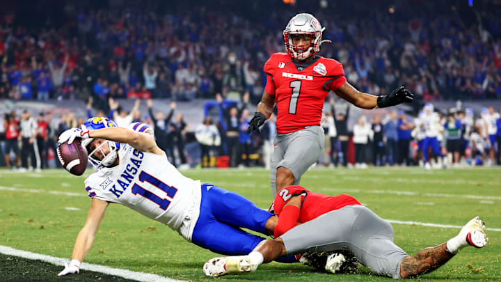 Dec 26, 2023; Phoenix, AZ, USA; Kansas Jayhawks wide receiver Luke Grimm (11) scores a touchdown against UNLV Rebels defensive back Jaxen Turner (2) during the second half in the Guaranteed Rate Bowl at Chase Field.