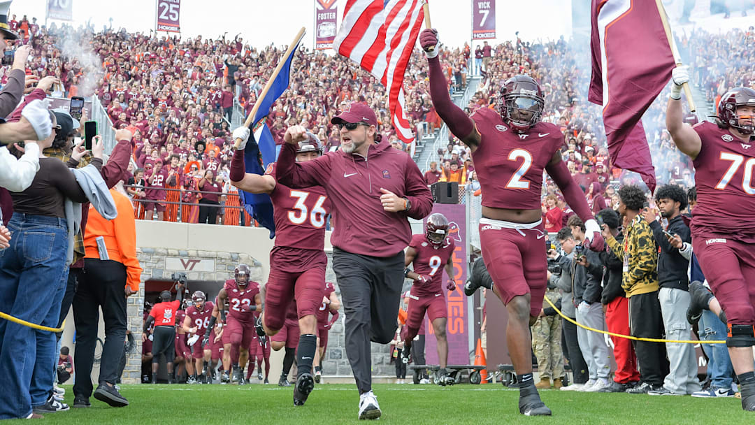 Nov 9, 2024; Blacksburg, Virginia, USA;  Virginia Tech Hokies head coach Brent Pry leads his team onto the field with Virginia Tech Hokies wide receiver Takye Heath (2) before the game at Lane Stadium. Mandatory Credit: Brian Bishop-Imagn Images