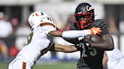 Oct 19, 2024; Louisville, Kentucky, USA; Louisville Cardinals running back Isaac Brown (25) runs the ball against Miami Hurricanes defensive back D'Yoni Hill (19) during the first half at L&N Federal Credit Union Stadium. Mandatory Credit: Jamie Rhodes-Imagn Images
