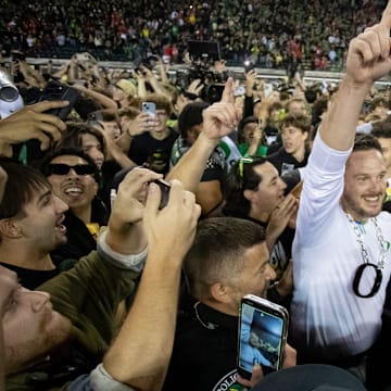 Coach Dan Lanning celebrates amid a crowd of fans on the field as No. 3 Oregon knocked off No. 2 Ohio State 32-31 on Saturday at Autzen Stadium in Eugene, Ore.