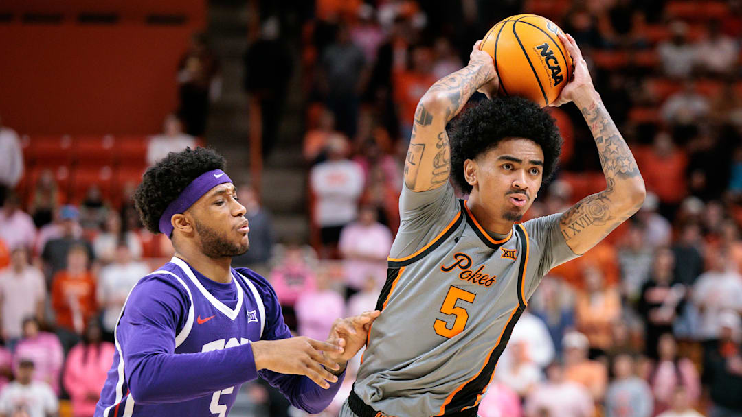 Feb 14, 2026; Stillwater, Oklahoma, USA; Oklahoma State Cowboys guard Vyctorius Miller (5) passes around TCU Horned Frogs forward Micah Robinson (5) during the first half at Gallagher-Iba Arena. 