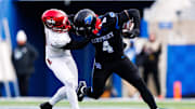 Nov 30, 2024; Lexington, Kentucky, USA; Kentucky Wildcats running back Chip Trayanum (4) is tackled by Louisville Cardinals defensive back Tahveon Nicholson (23) during the fourth quarter at Kroger Field. Mandatory Credit: Jordan Prather-Imagn Images