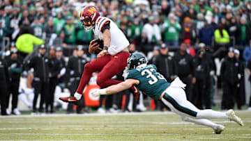 Jan 26, 2025; Philadelphia, PA, USA; Washington Commanders quarterback Jayden Daniels (5) leaps to avoid Philadelphia Eagles cornerback Cooper DeJean (33) during the first half in the NFC Championship game at Lincoln Financial Field. Mandatory Credit: Eric Hartline-Imagn Images