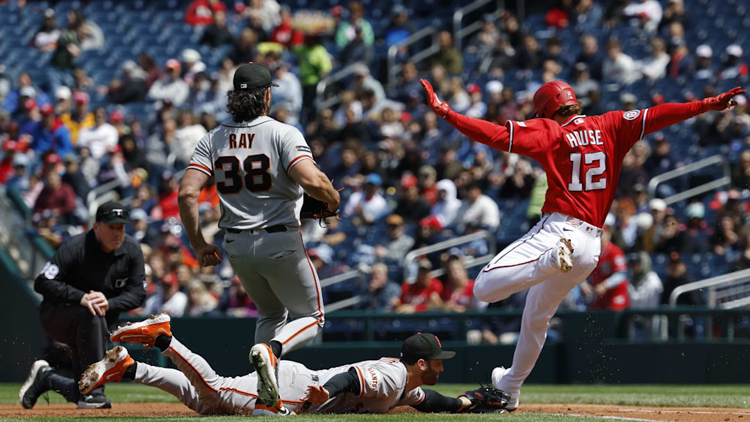 Apr 19, 2026; Washington, District of Columbia, USA; Washington Nationals third baseman Brady House (12) reaches first base ahead of a diving tag by San Francisco Giants third baseman Casey Schmitt (10) as Giants starting pitcher Robbie Ray (38) looks on during the first inning at Nationals Park. Mandatory Credit: Geoff Burke-Imagn Images