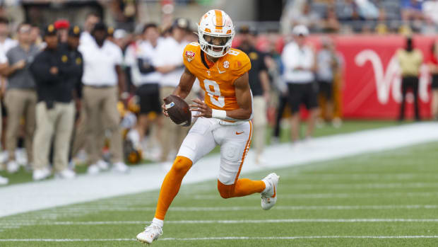 Tennessee Volunteers quarterback Nico Iamaleava avoids a tackle during a college football game in the SEC.
