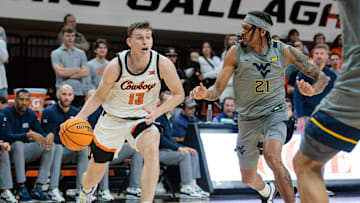 Jan 27, 2024; Stillwater, Oklahoma, USA; Oklahoma State Cowboys guard Connor Dow (13) drives around West Virginia Mountaineers guard RaeQuan Battle (21) during the first half at Gallagher-Iba Arena. Mandatory Credit: William Purnell-Imagn Images