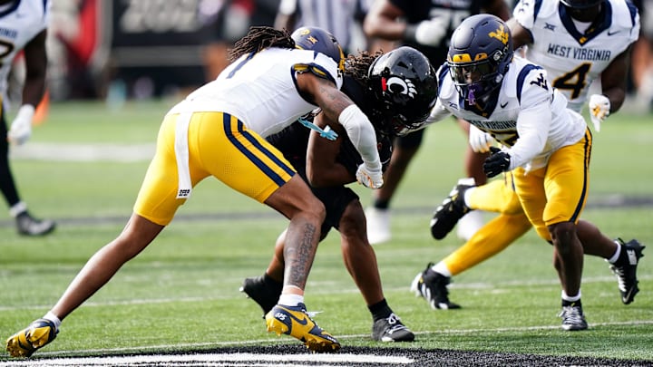 West Virginia Mountaineers cornerback Garnett Hollis Jr. (1) and West Virginia Mountaineers safety Anthony Wilson Jr. (12) tackle Cincinnati Bearcats wide receiver Jamoi Mayes (10) in the first quarter of a college football game between the Cincinnati Bearcats and West Virginia Mountaineers, Saturday, Nov. 9, 2024, at Nippert Stadium in Cincinnati.