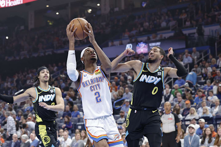 Oklahoma City Thunder guard Shai Gilgeous-Alexander drives to the basket beside Indiana Pacers guard Tyrese Haliburton.
