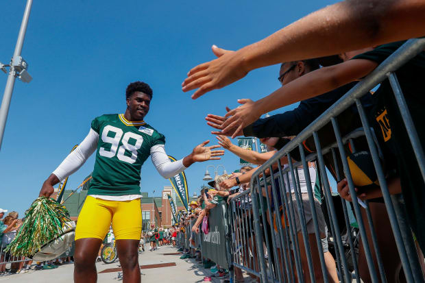 Green Bay Packers defensive lineman Kenneth Odumegwu slaps hands with fans before practice.