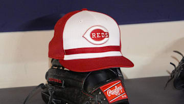 Apr 4, 2025; Milwaukee, Wisconsin, USA; Cincinnati Reds hat and glove rest on the bench in the dugout before a game against the Milwaukee Brewers at American Family Field. Mandatory Credit: Michael McLoone-Imagn Images