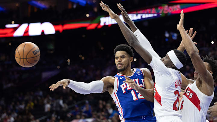 Nov 2, 2023; Philadelphia, Pennsylvania, USA; Philadelphia 76ers forward Tobias Harris (12) passes the ball past Toronto Raptors forward Chris Boucher (25) during the second quarter at Wells Fargo Center. Mandatory Credit: Bill Streicher-USA TODAY Sports