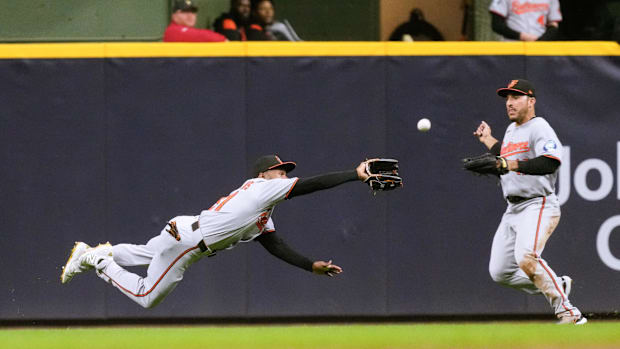Baltimore Orioles outfielder Cedric Mullins diving for a catch in the outfield in a gray uniform. 