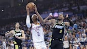 Oklahoma City Thunder guard Shai Gilgeous-Alexander drives to the basket beside Indiana Pacers guard Tyrese Haliburton.