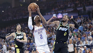 Oklahoma City Thunder guard Shai Gilgeous-Alexander drives to the basket beside Indiana Pacers guard Tyrese Haliburton.